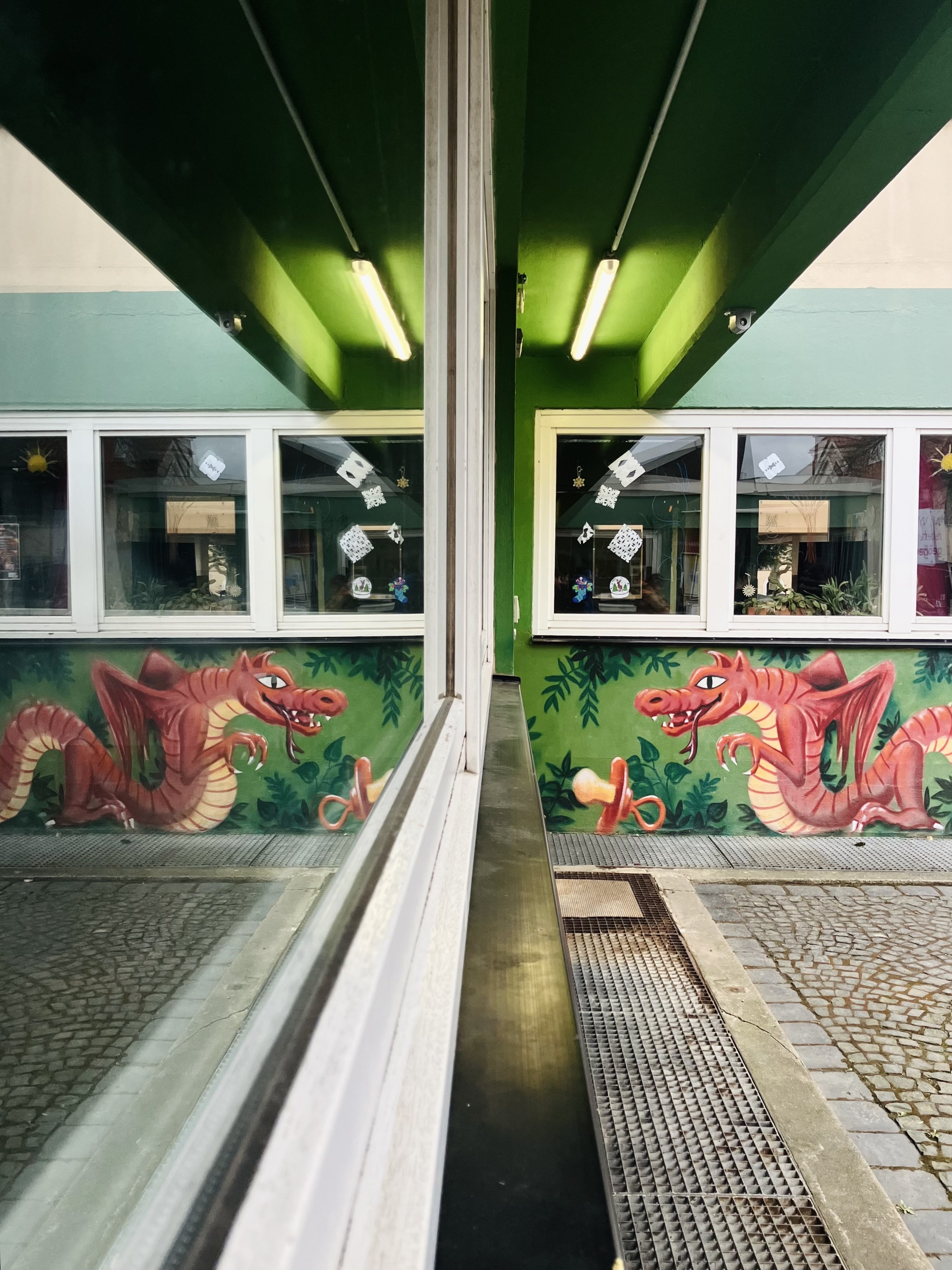 Foto von der Hauswand des Kinder- und Jugendhaus Sindlingen. Die Hauswand ist mit einem roten Drachen bemalt. Darüber sind drei Fenster mit weißen Rahmen.